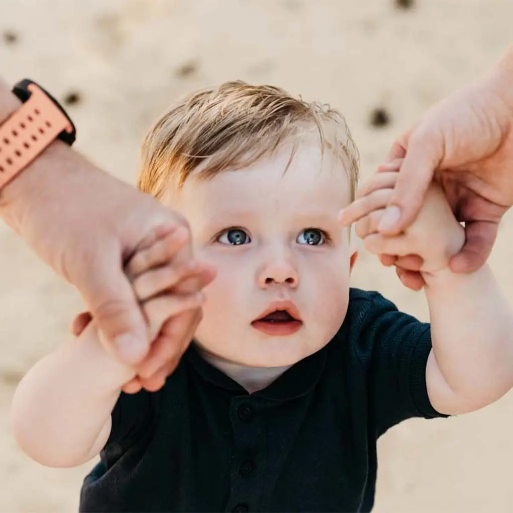 Kind kijkt omhoog terwijl ouders zijn handen vasthouden tijdens de familie fotoshoot op het Wekeromse Zand